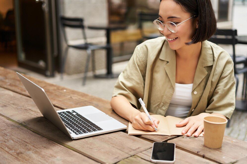 An ecommerce content writer taking down notes in front of her laptop