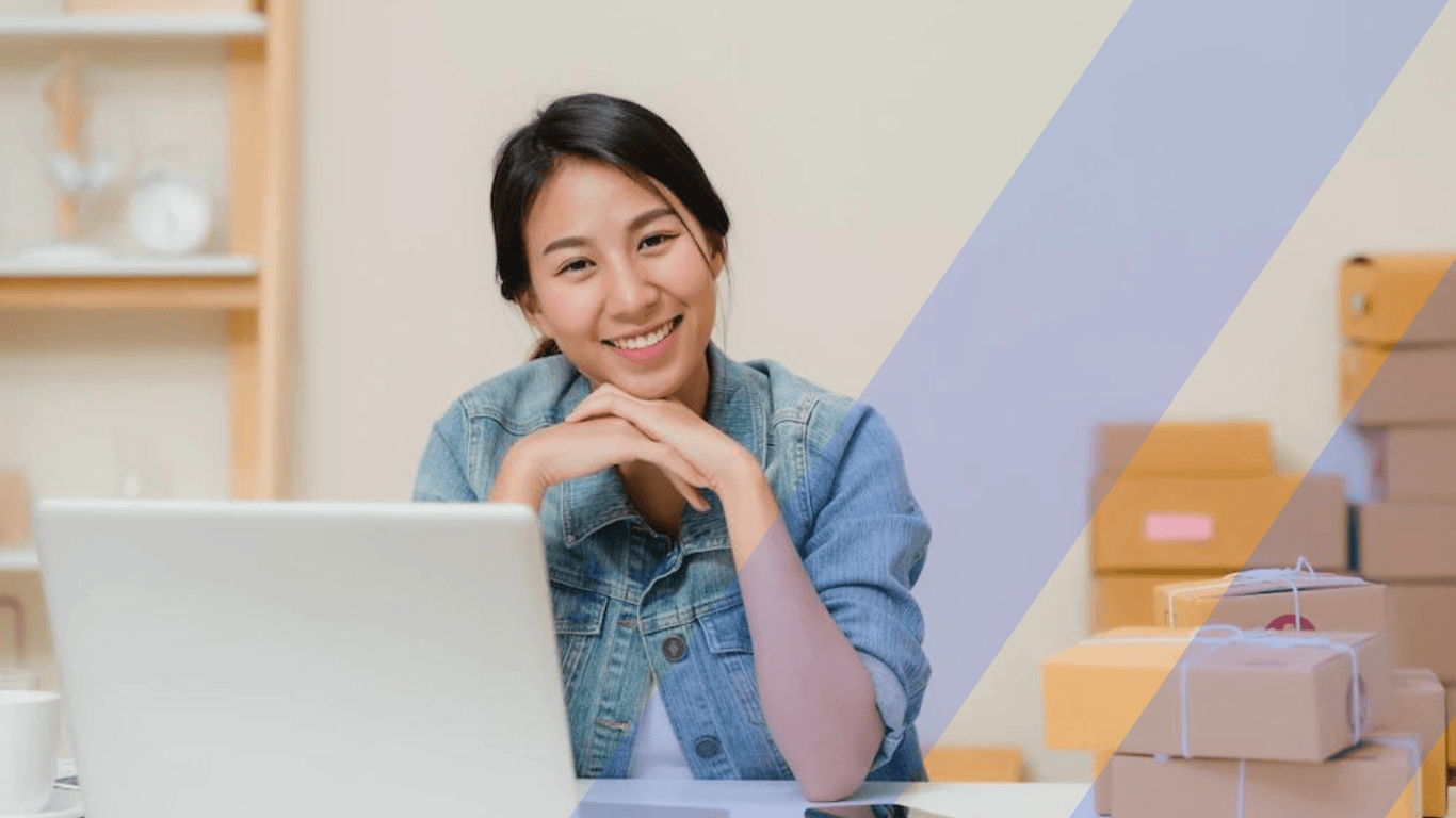 an online retailer smiling in front of a laptop
