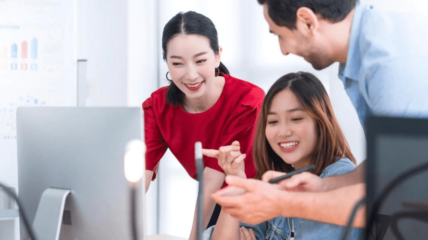 A group of social media content moderators consulting in front of a desktop computer