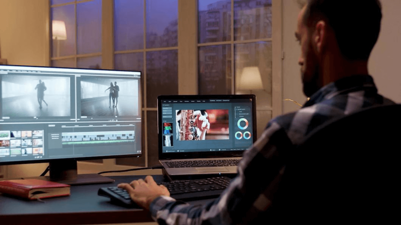 A motion graphics designer working at the studio in front of his desktop computer and laptop