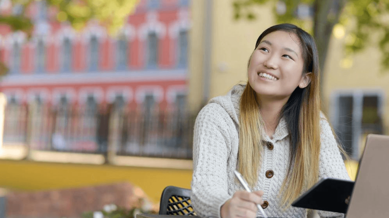 An asian product content writer smiling while working outdoors